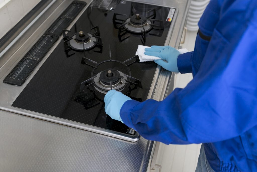 コンロを清掃する作業員の手元